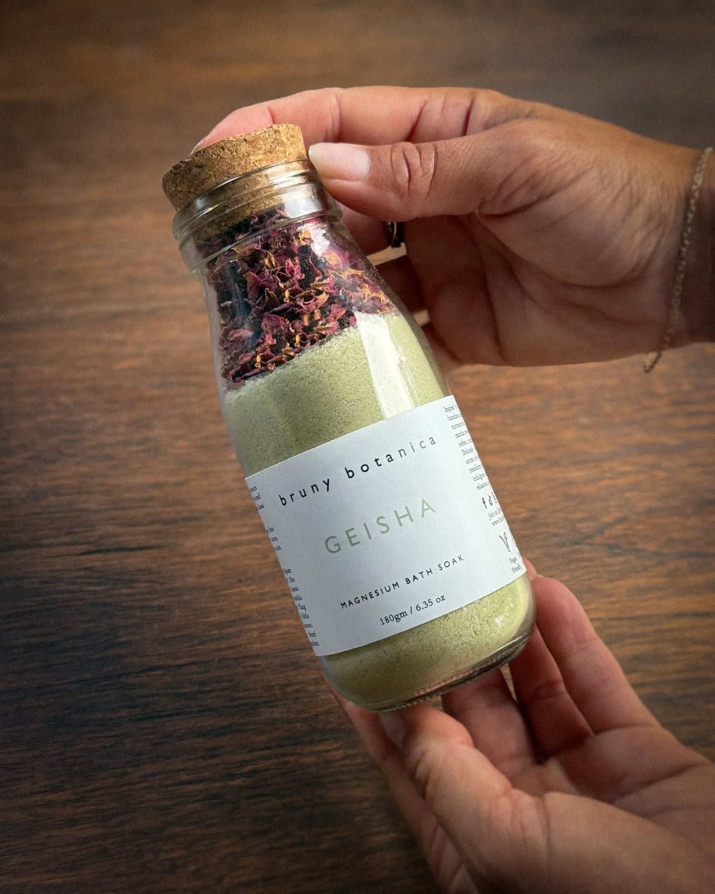 A Geisha Magnesium Bath Soak being held against a wooden backdrop