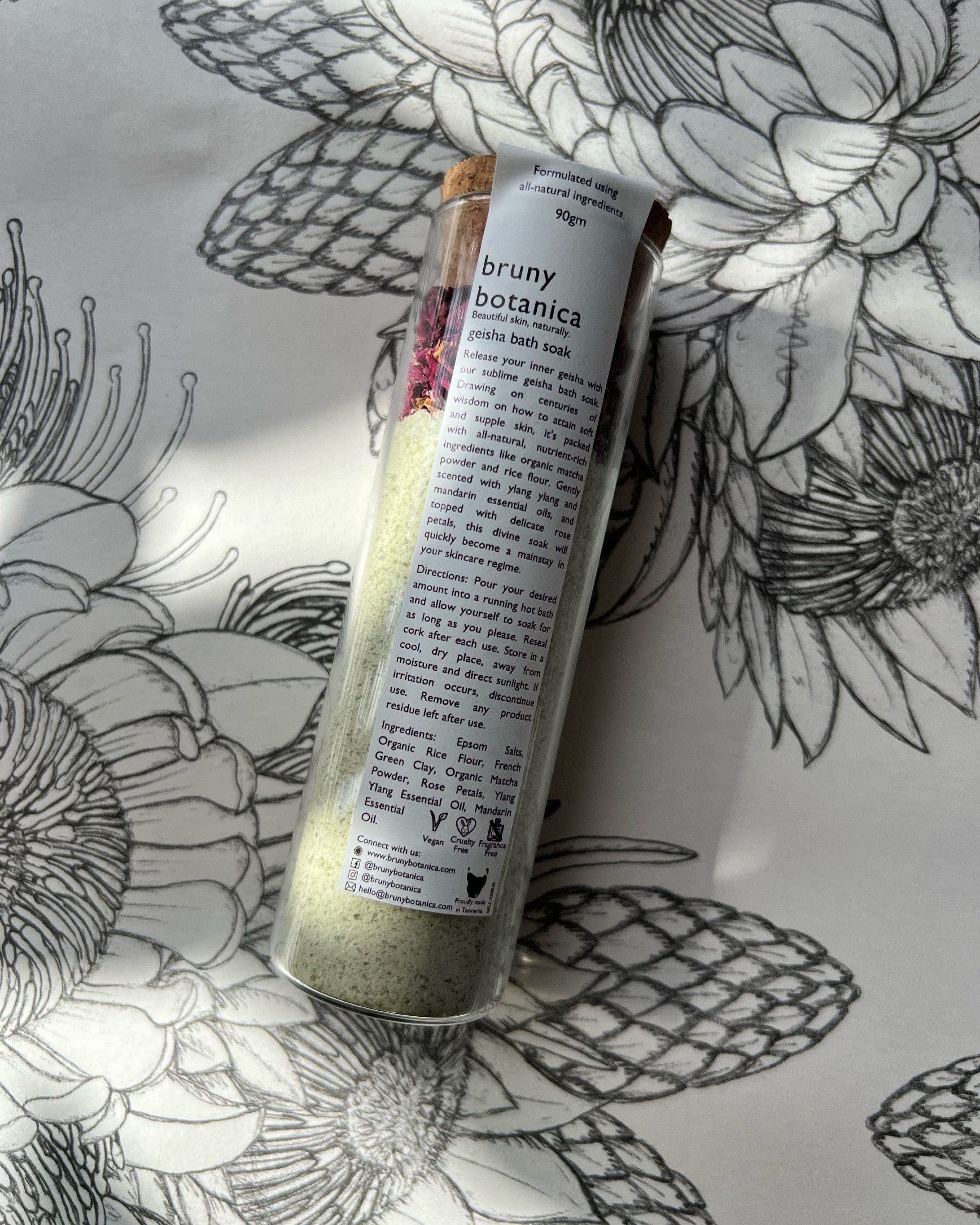 A Geisha Magnesium Bath Soak tube sits against a floral background