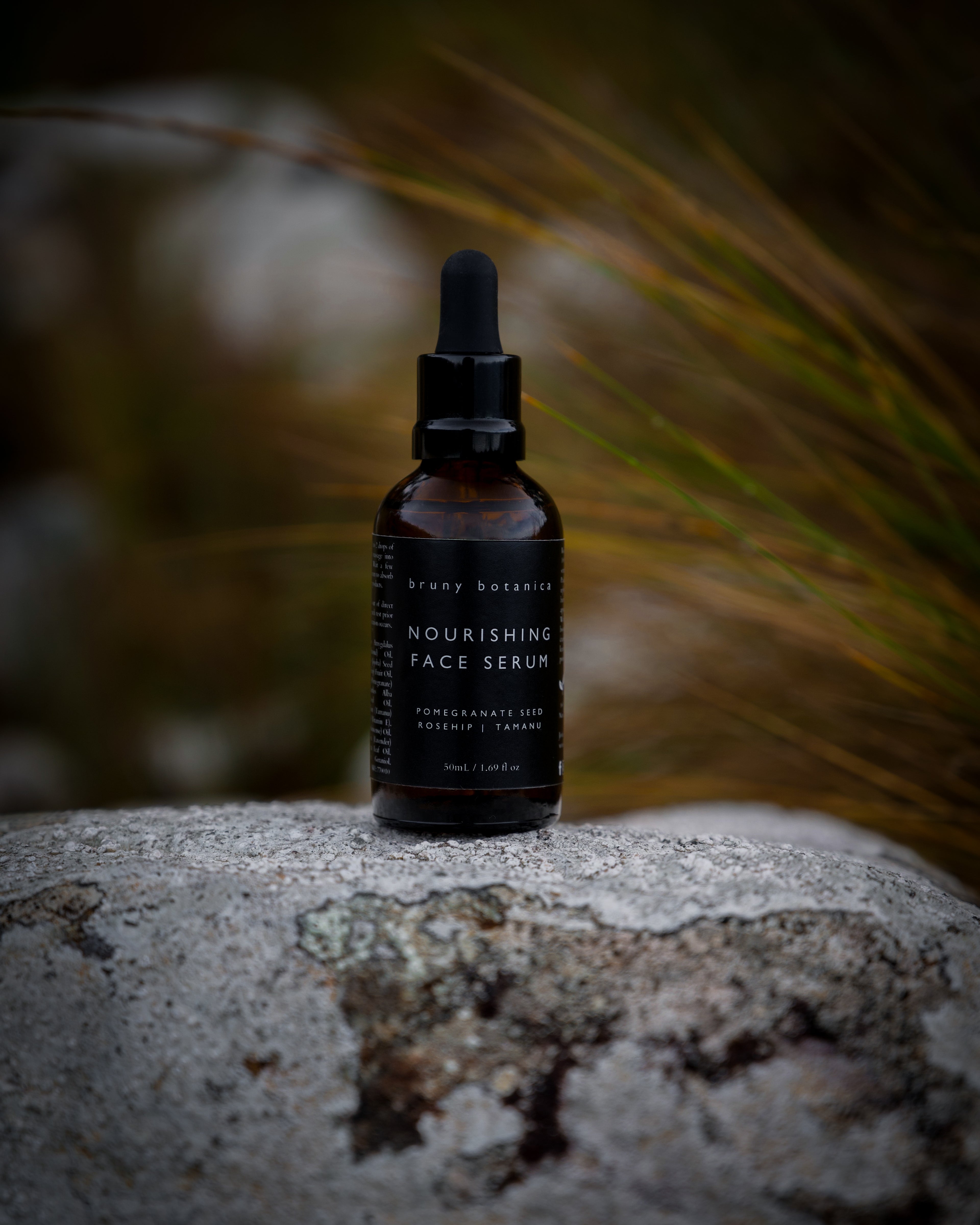 Bottle of nourishing face serum on a stone surface with a blurred natural background