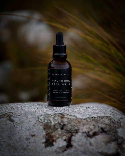 Bottle of nourishing face serum on a stone surface with a blurred natural background