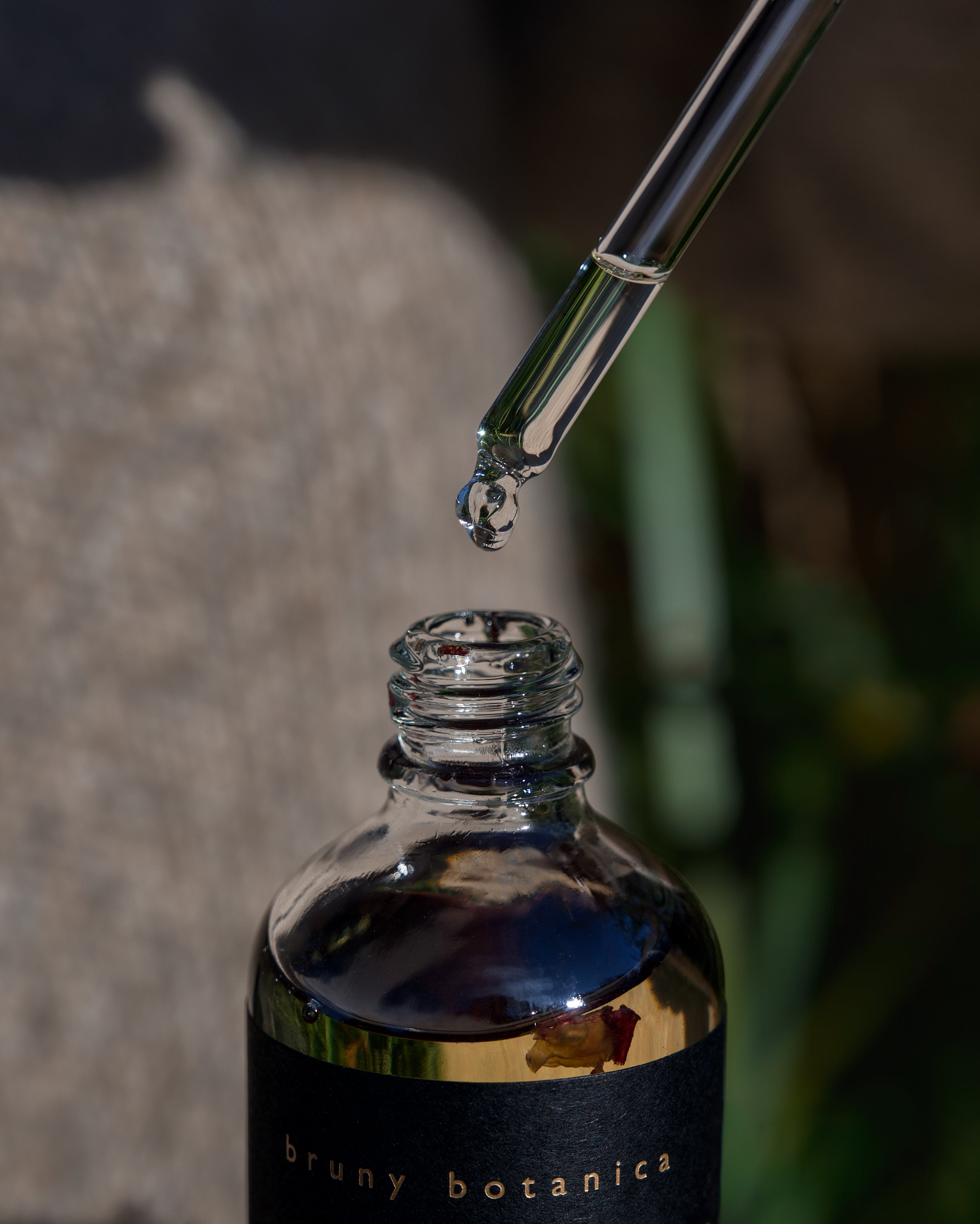 A close up of the Rose Radiance Elixir Body Oil dropper and bottle