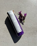 A tube of Tasmanian Lavender Magnesium Bath Soak on a concrete surface next to a small bundle of lavender.