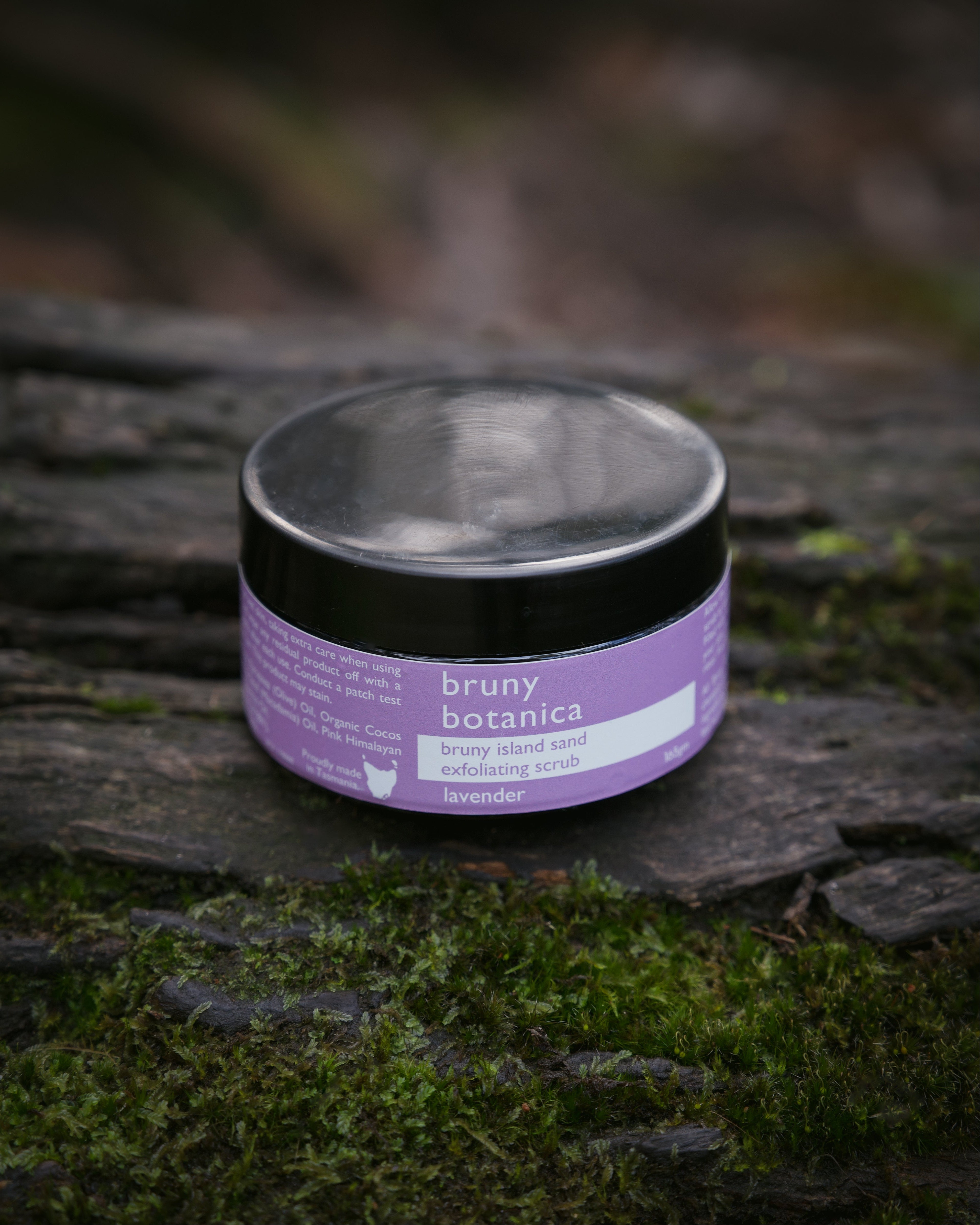 A lavender boddy scrub sits atop a mossy log