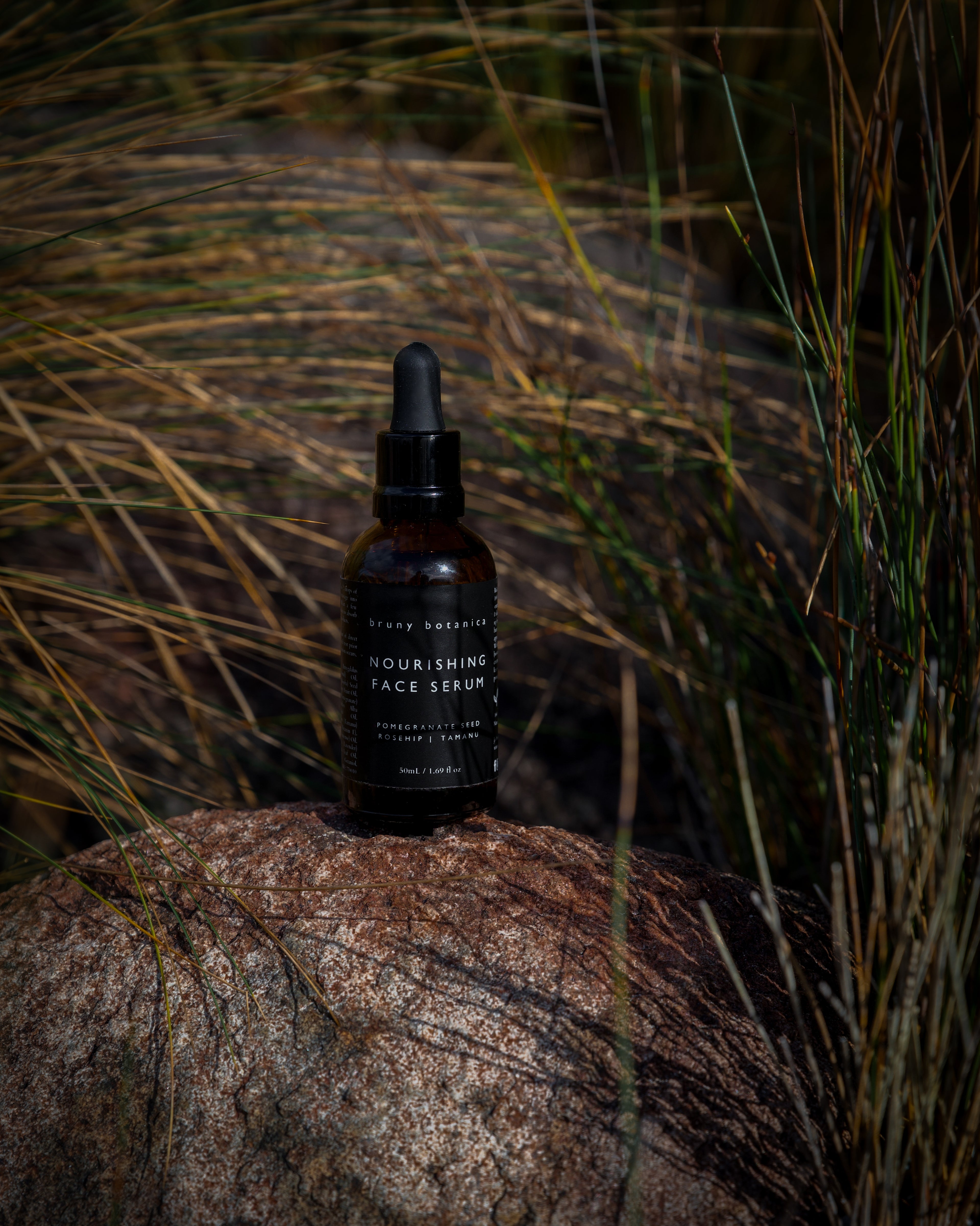 Bottle of Nourishing Face Serum on a rock with grass in the background